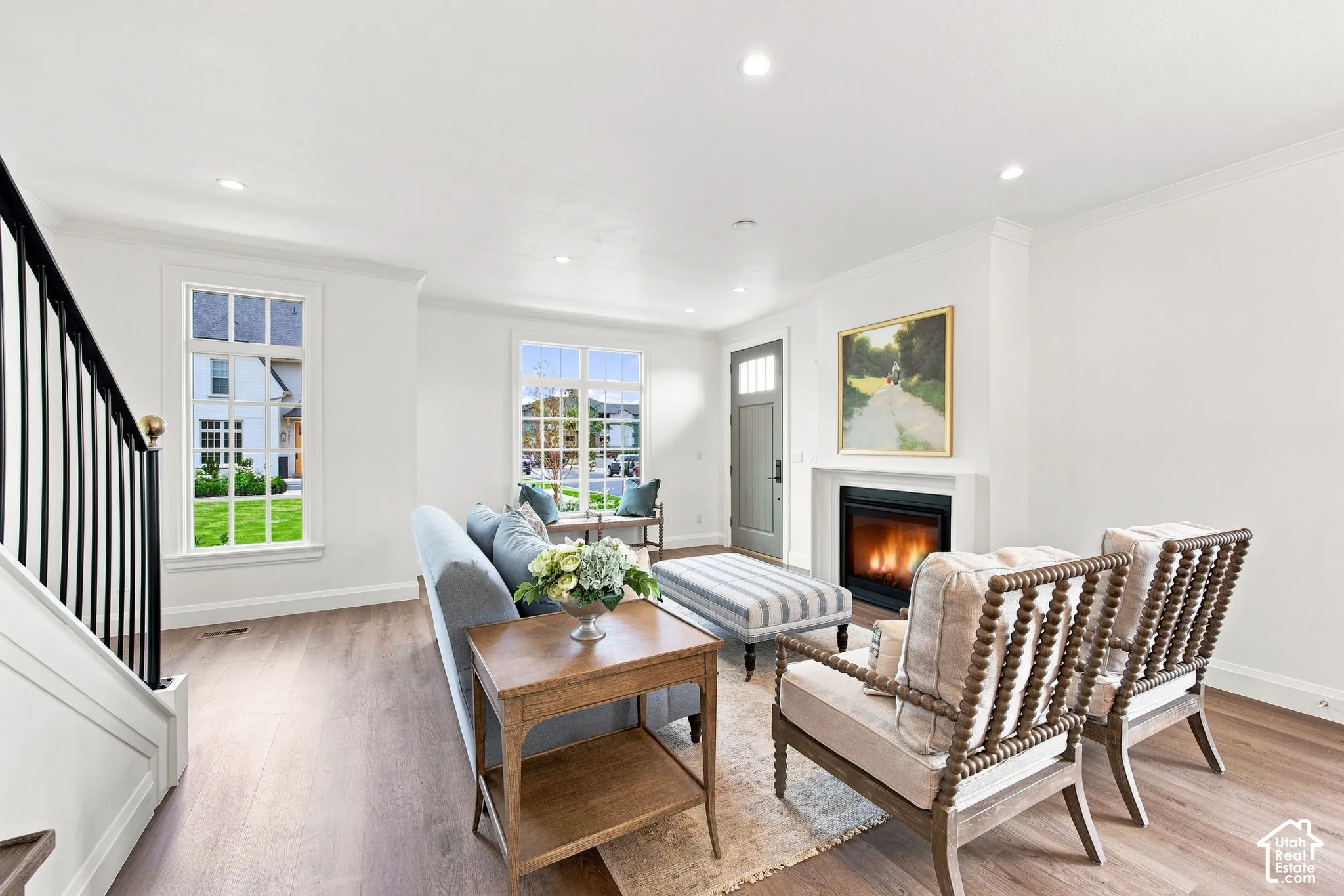 Model Home - Bright living area featuring wood-finish flooring, a contemporary fireplace, multiple windows with white trim, a solid entry door, and recessed lighting