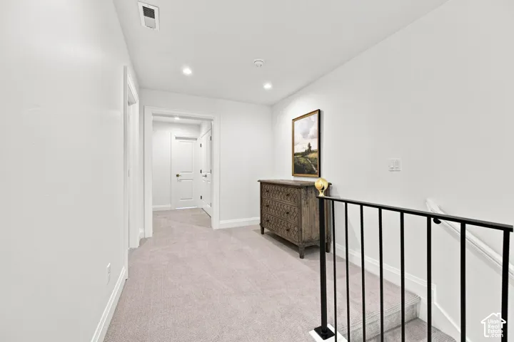 Model Home - Recessed lighting, light gray carpeting, white walls, white trim, and a black metal railing