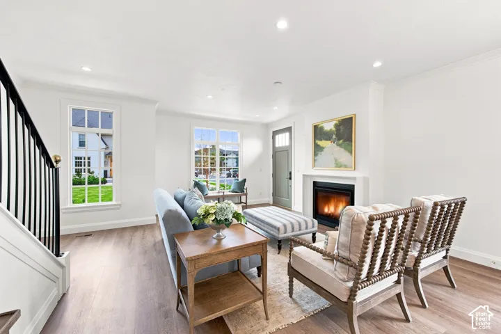 Model Home - Bright living area featuring wood-finish flooring, a contemporary fireplace, multiple windows with white trim, a solid entry door, and recessed lighting