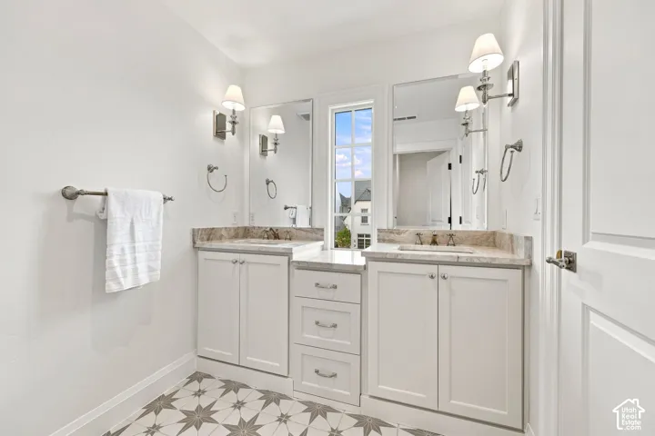 Model Home - Dual white vanities with integrated sinks, framed mirrors, and wall-mounted sconces