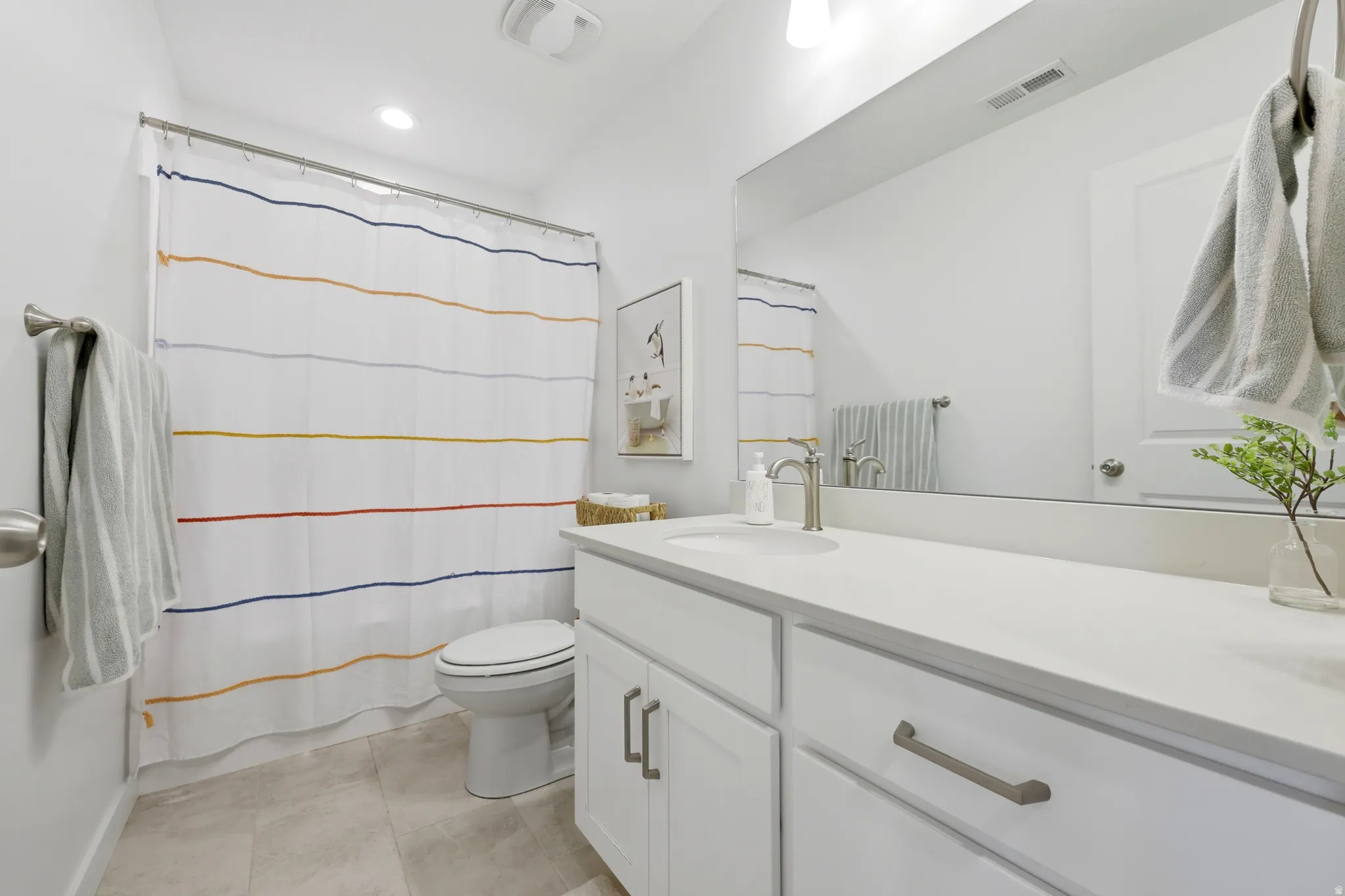 Modern bathroom featuring a white vanity with dual sink configuration, quartz countertop, chrome fixtures, and polished hardware