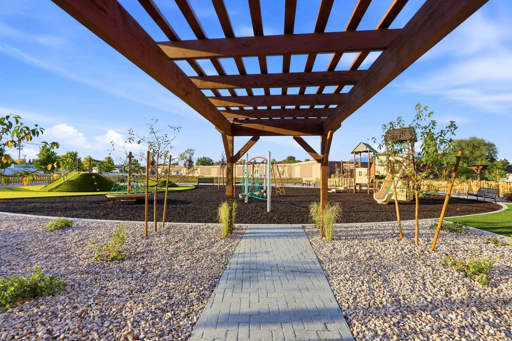 Outdoor entertaining space featuring a substantial wood-frame pergola with slatted roof design, pea gravel landscaping, and permeable paver walkway