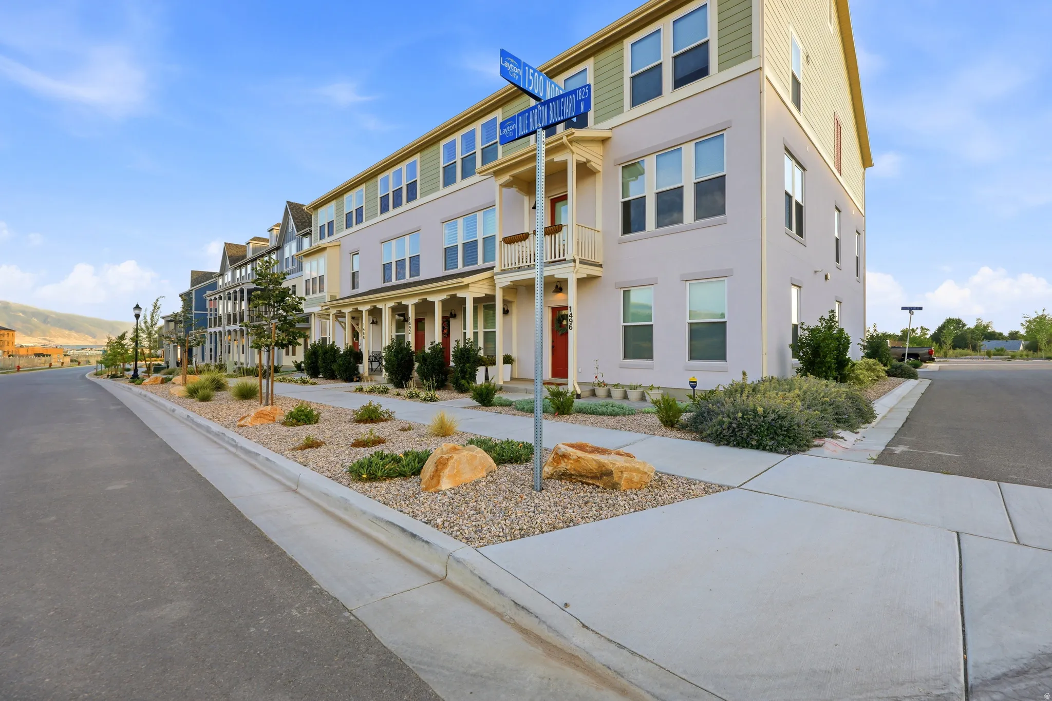 Townhome exterior featuring multi-story design with varied siding, individual balconies, and red entry doors