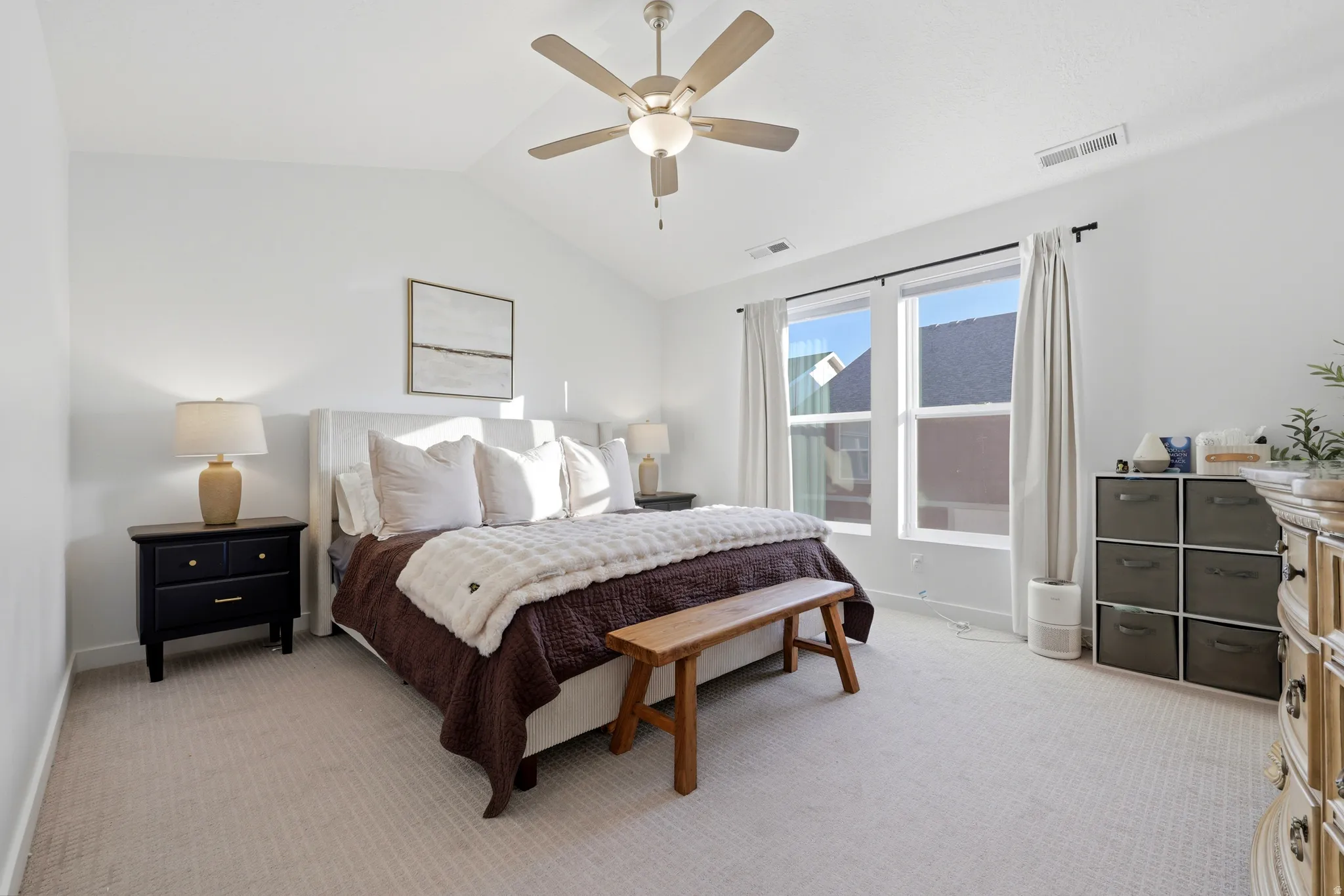 Spacious primary bedroom featuring neutral carpet flooring, ceiling fan with integrated lighting, dual nightstands with table lamps, and expansive glass sliding doors opening to natural light