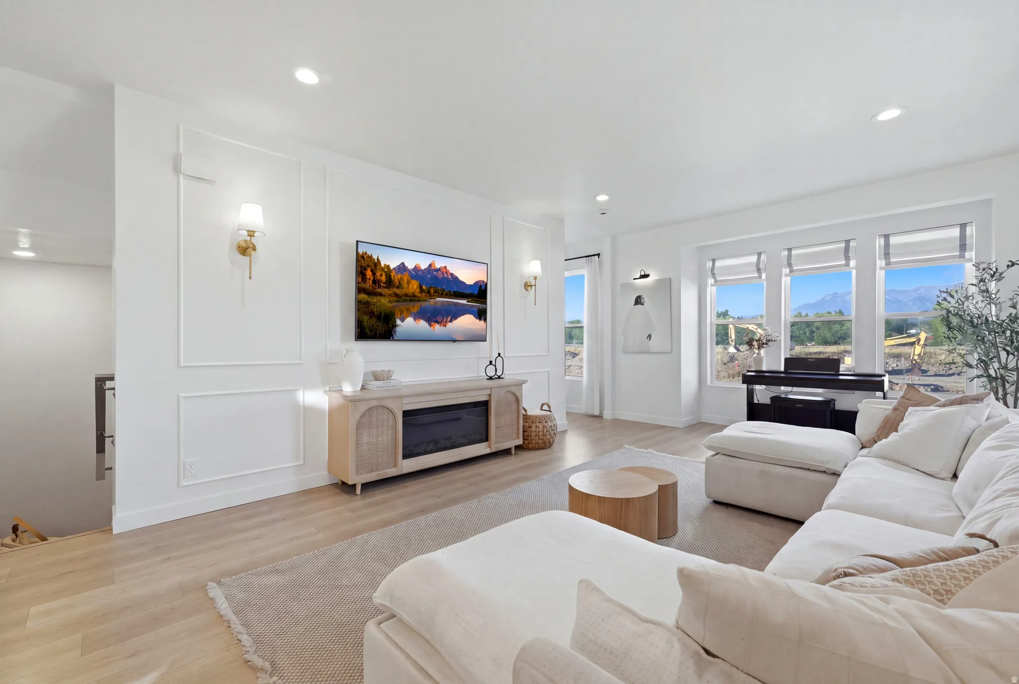 Bright, open-concept living area featuring recessed ceiling lighting, a wood-finish plank floor, and expansive multi-pane windows with mountain vistas