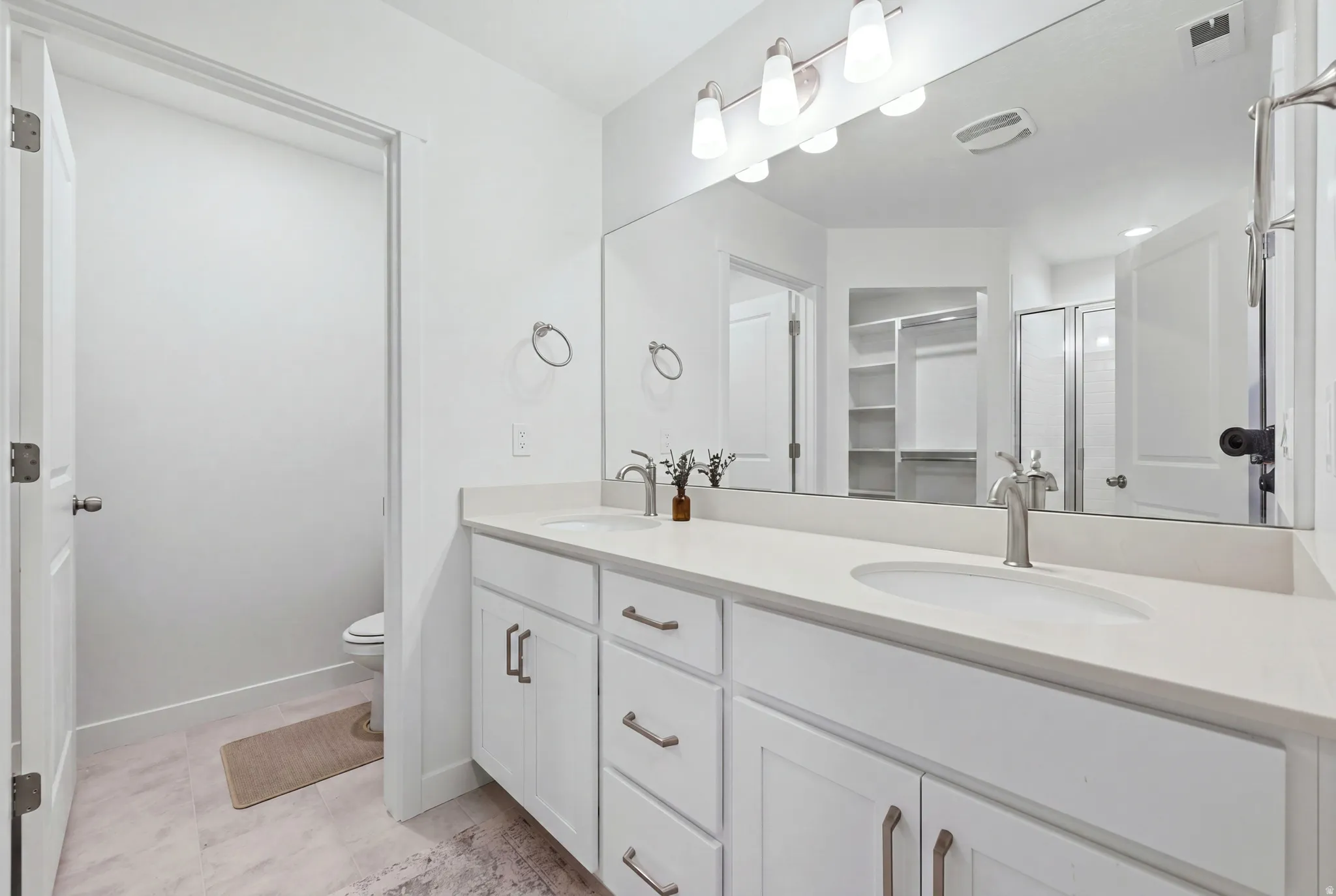 Double vanity with white cabinetry, brushed nickel hardware, and light-toned countertops