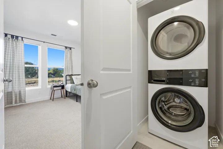 Integrated laundry closet with stacked appliances, featuring white doors and light-colored flooring