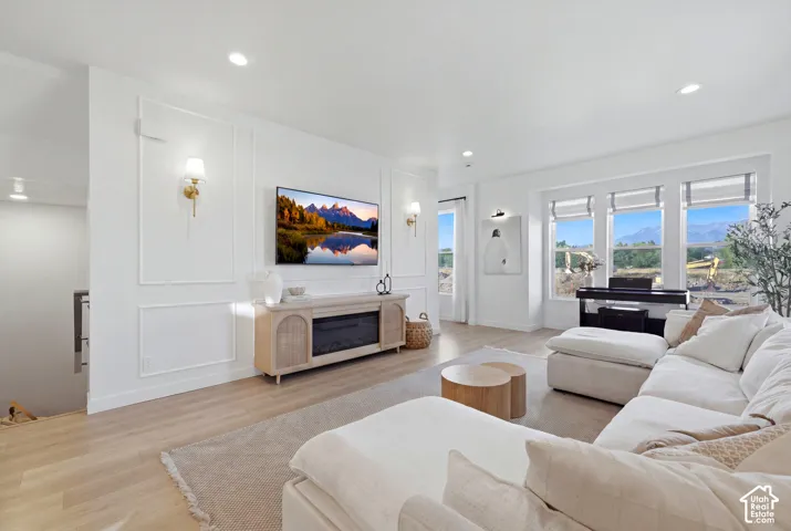 Bright, open-concept living area featuring recessed ceiling lighting, a wood-finish plank floor, and expansive multi-pane windows with mountain vistas