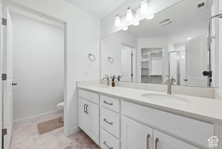 Double vanity with white cabinetry, brushed nickel hardware, and light-toned countertops