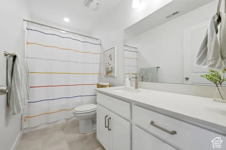 Modern bathroom featuring a white vanity with dual sink configuration, quartz countertop, chrome fixtures, and polished hardware