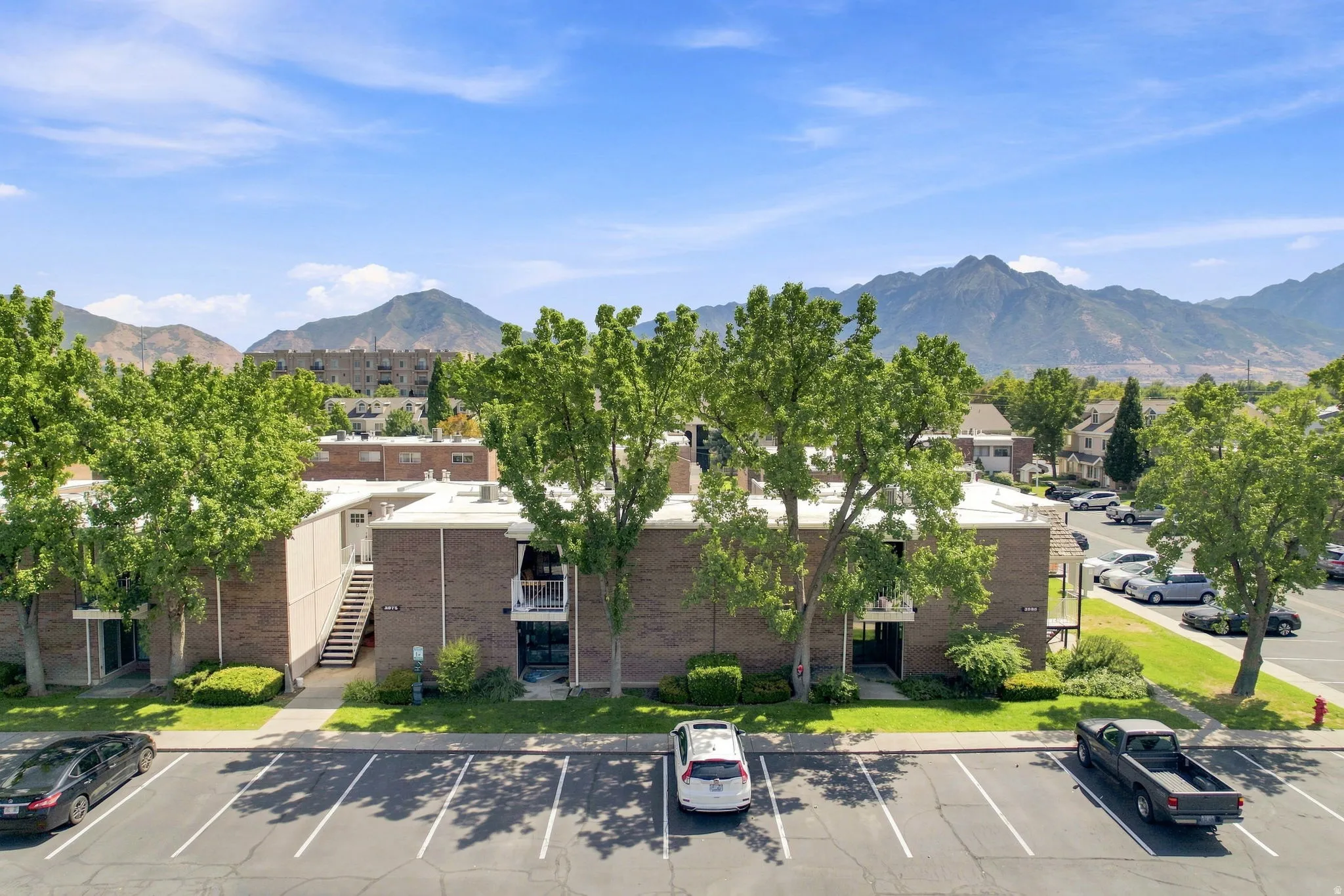 Brick exterior with mature trees, landscaped grounds, and paved parking
