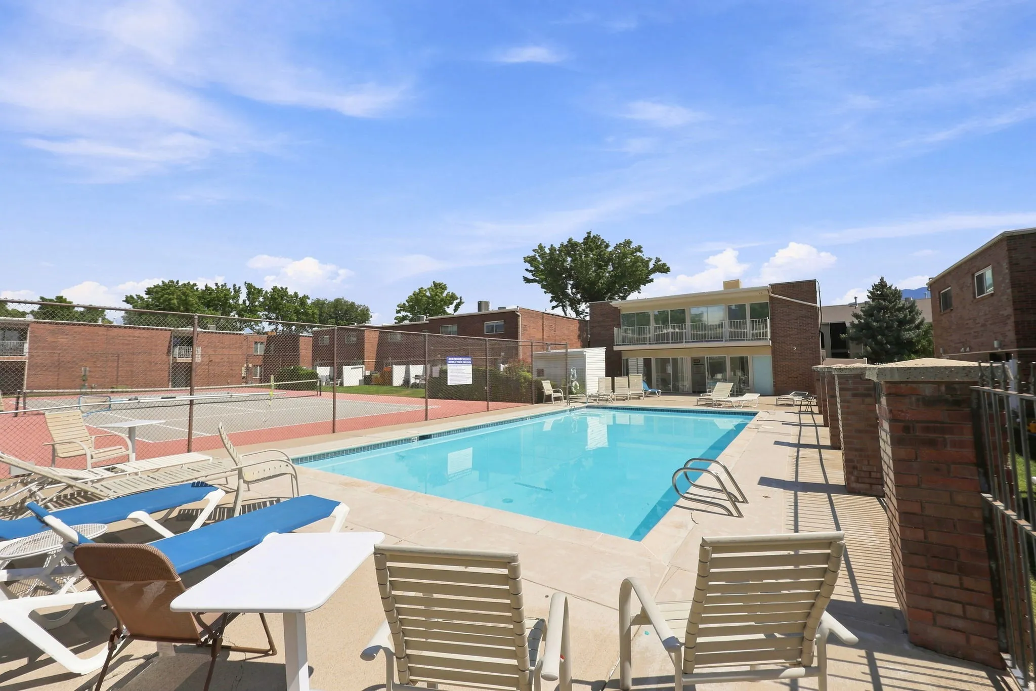 Resort-style swimming pool with expansive sun deck, lounge seating areas, and mature landscaping