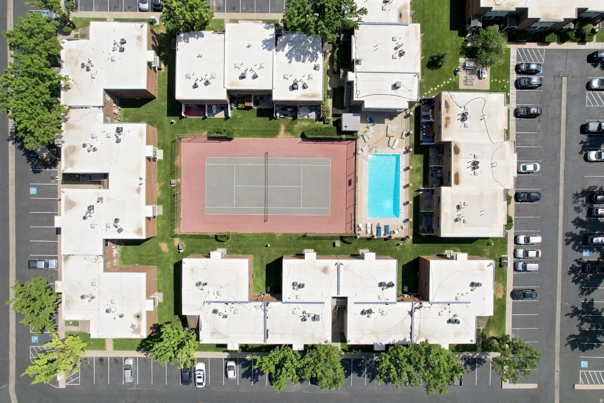 Aerial perspective of the property featuring multiple buildings, surface parking areas, and mature landscaping