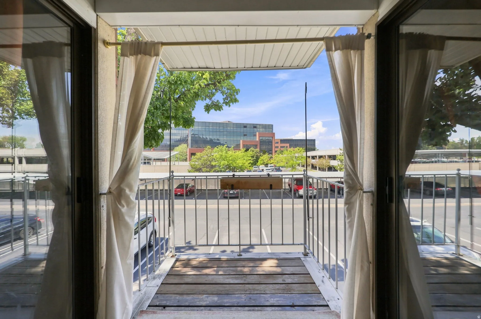 Sliding glass door access to a balcony with metal railing and wood-finish flooring