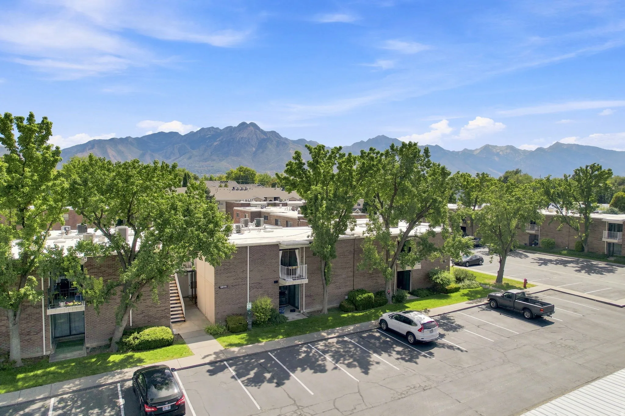 Brick exterior with balconies, ample parking, mature trees, and mountain scenery