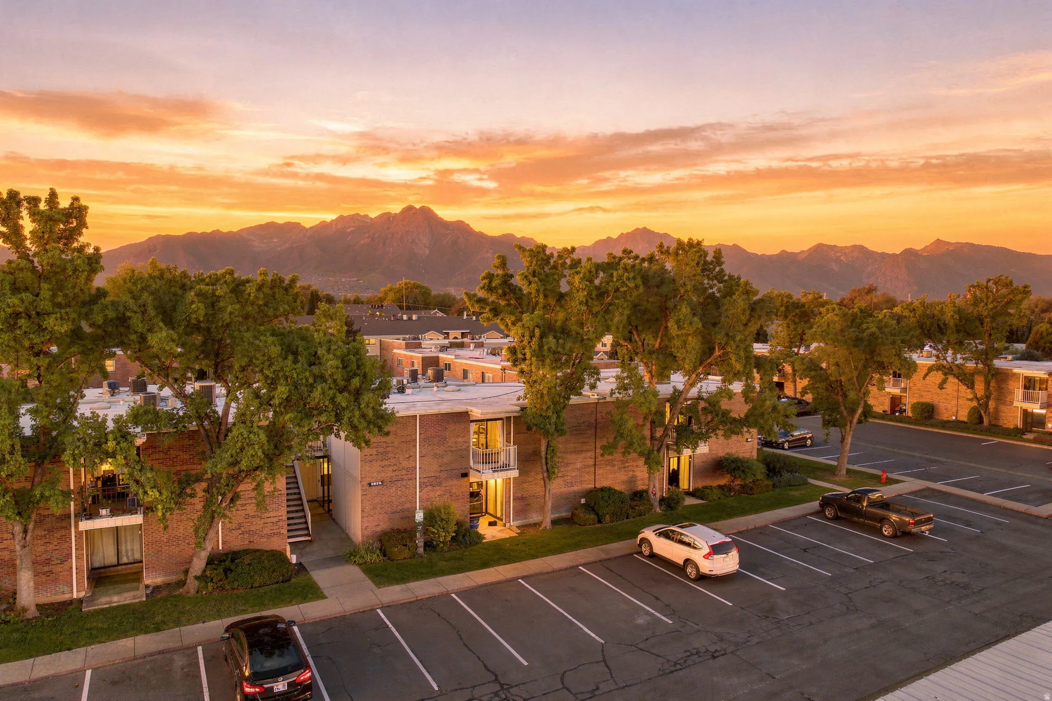 Brick exterior construction with balconies, ample surface parking, and mature trees