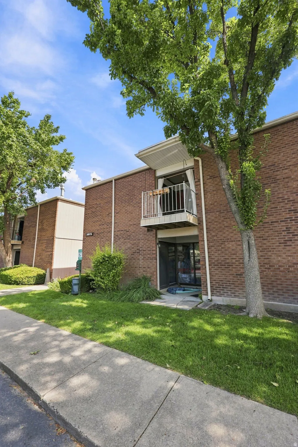 Brick exterior with white trim, featuring a private balcony and ground-level patio