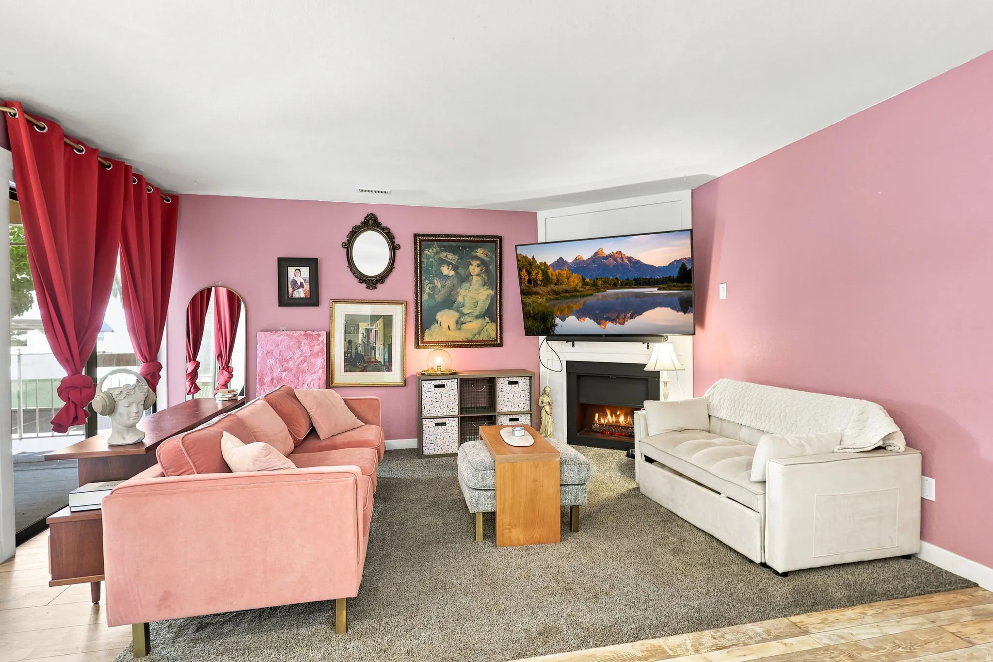 Living area featuring a wall-mounted fireplace, wall-mounted television, and wood-finish flooring