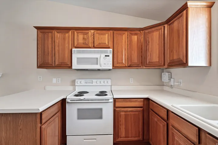 Kitchen featuring wood-finish cabinetry, solid surface countertops, a white electric range, and an over-the-range microwave