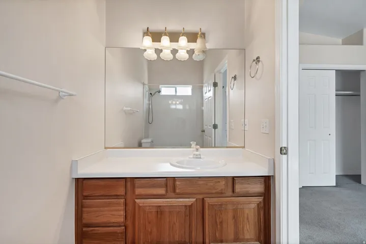 Vanity with wood-finish cabinetry, integrated sink, and laminate countertop