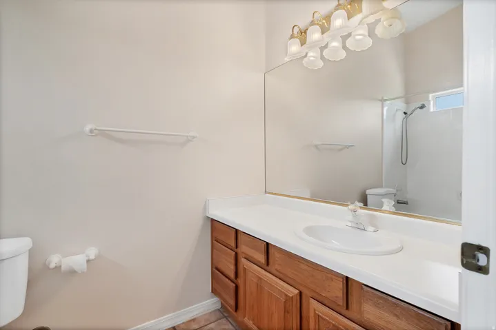 Vanity with wood-finish cabinetry, white countertop, and integrated sink