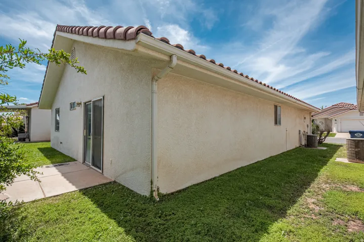 Stucco exterior with a tile roof, sliding glass door, and concrete patio
