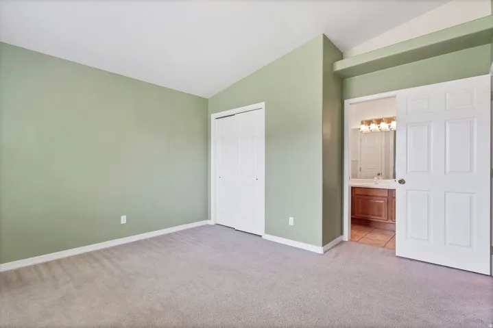 Carpeted bedroom with vaulted ceiling and a sliding closet door
