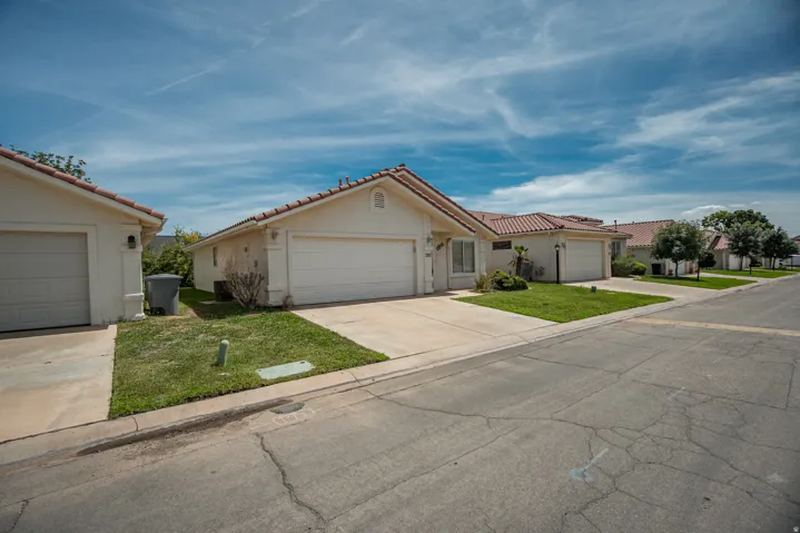 Single-story residence featuring a tile roof, an attached garage, a concrete driveway, and a grass lawn