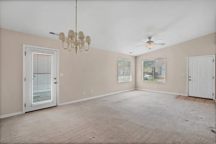 Spacious room featuring vaulted ceilings, light-toned carpeting, and multiple windows