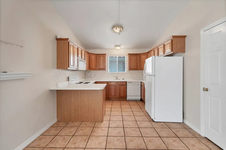U-shaped kitchen featuring wood-finish cabinetry, white countertops, and tile flooring