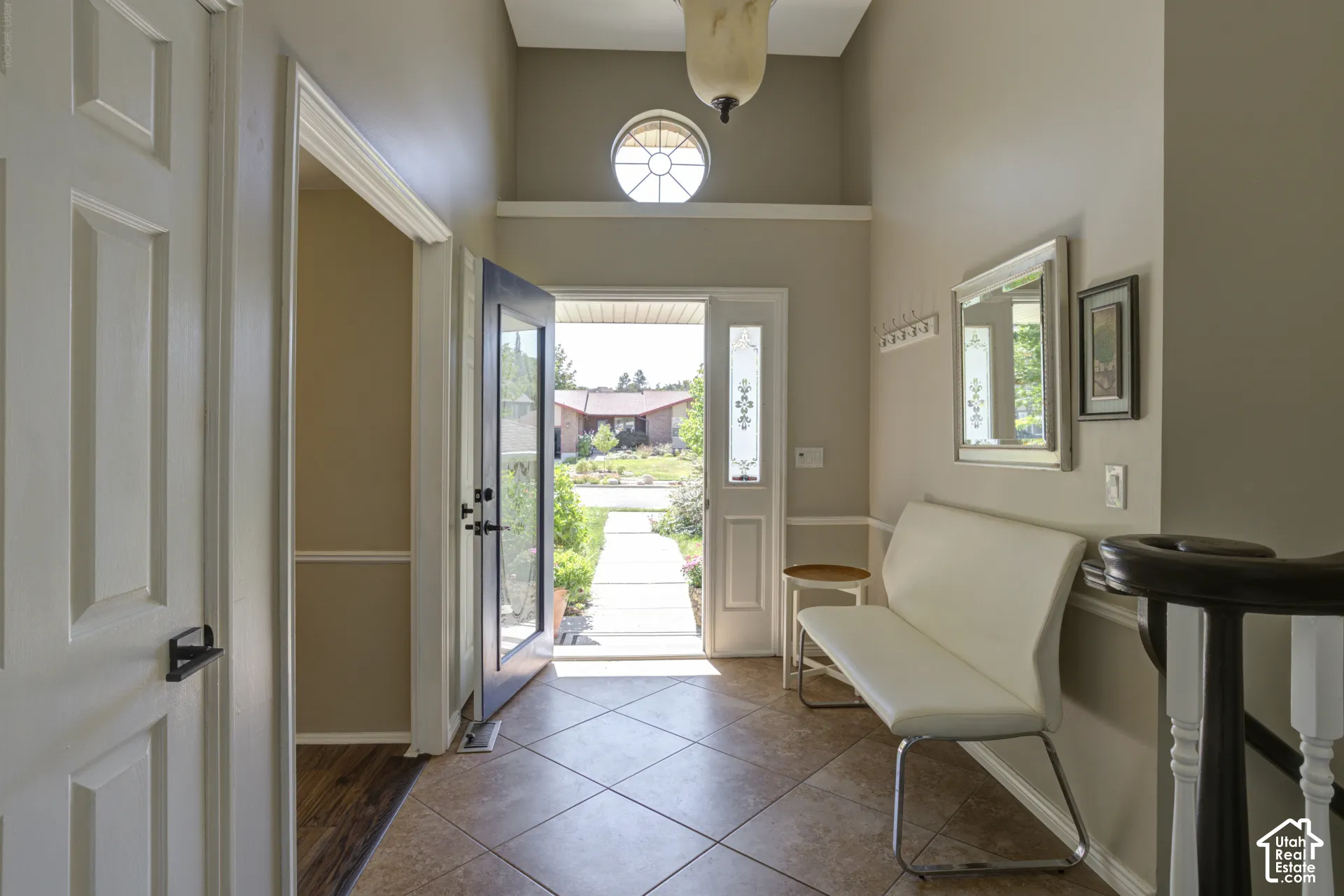 view from kitchen enty through the front dooway. A glass paneled front door with round transome window add to natural light in the area.