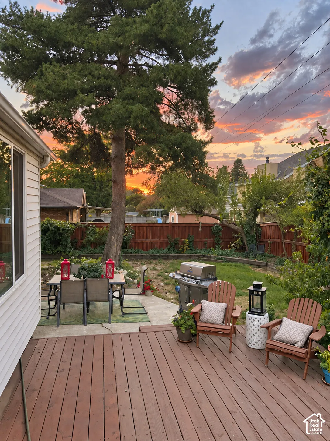 Expansive wood deck with a privacy fence, mature trees, and a concrete patio area
