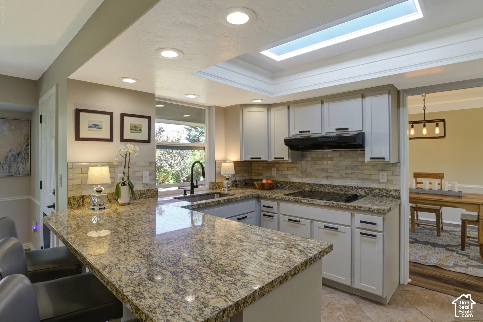 Kitchen featuring granite countertops, a marble tiled backsplash, newly refaced cabinetry, recessed lighting,
