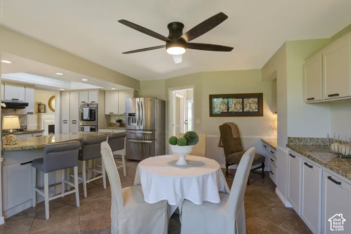 Open-concept kitchen with recessed lighting, fan, stainless steel appliances, and a breakfast bar