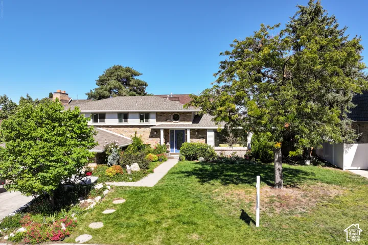 Brick and siding exterior, established landscaping, mature trees line the walkway to the front door.