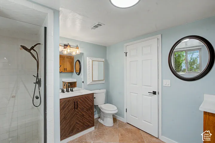 Laundryroom/bathroom featuring a walk-in shower with rainfall showerhead and hand shower, wood-finish vanity additional cabinet storage,tile flooring,