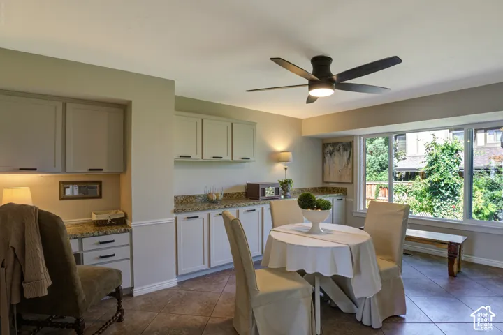 Built-in cabinetry with stone countertops, integrated workspace, and a ceiling fan with integrated lighting