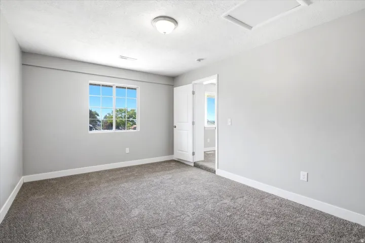 Neutral wall paint, plush carpet flooring, white trim, recessed lighting, and a multi-pane window