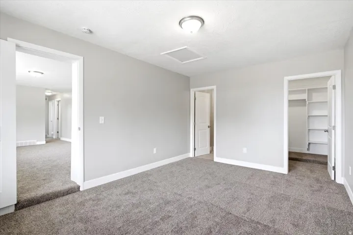 Neutral wall paint, ceiling-mounted light fixture, and plush carpet flooring