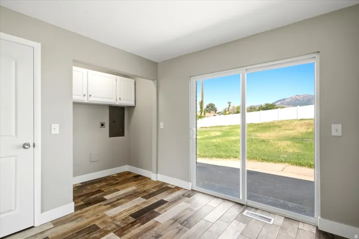 Wood-finish flooring, sliding glass door, white cabinetry, and a mountain backdrop