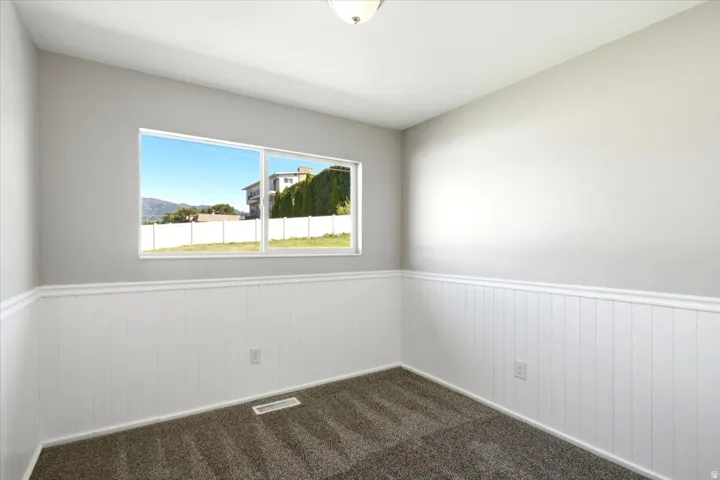 Grey carpeting, white beadboard wainscoting, white trim, and a white ceiling fixture