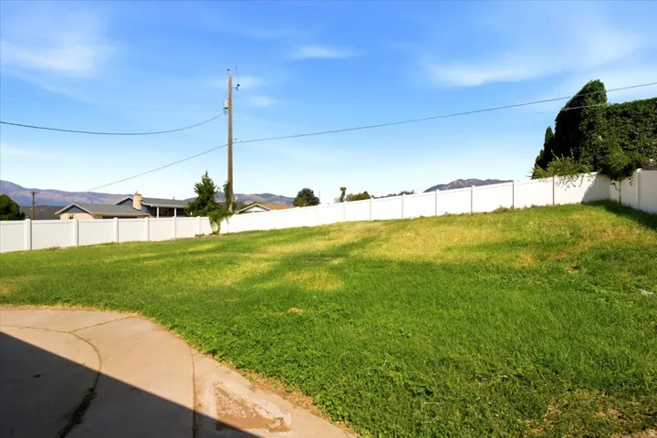 Expansive grassy lot bordered by a white privacy fence