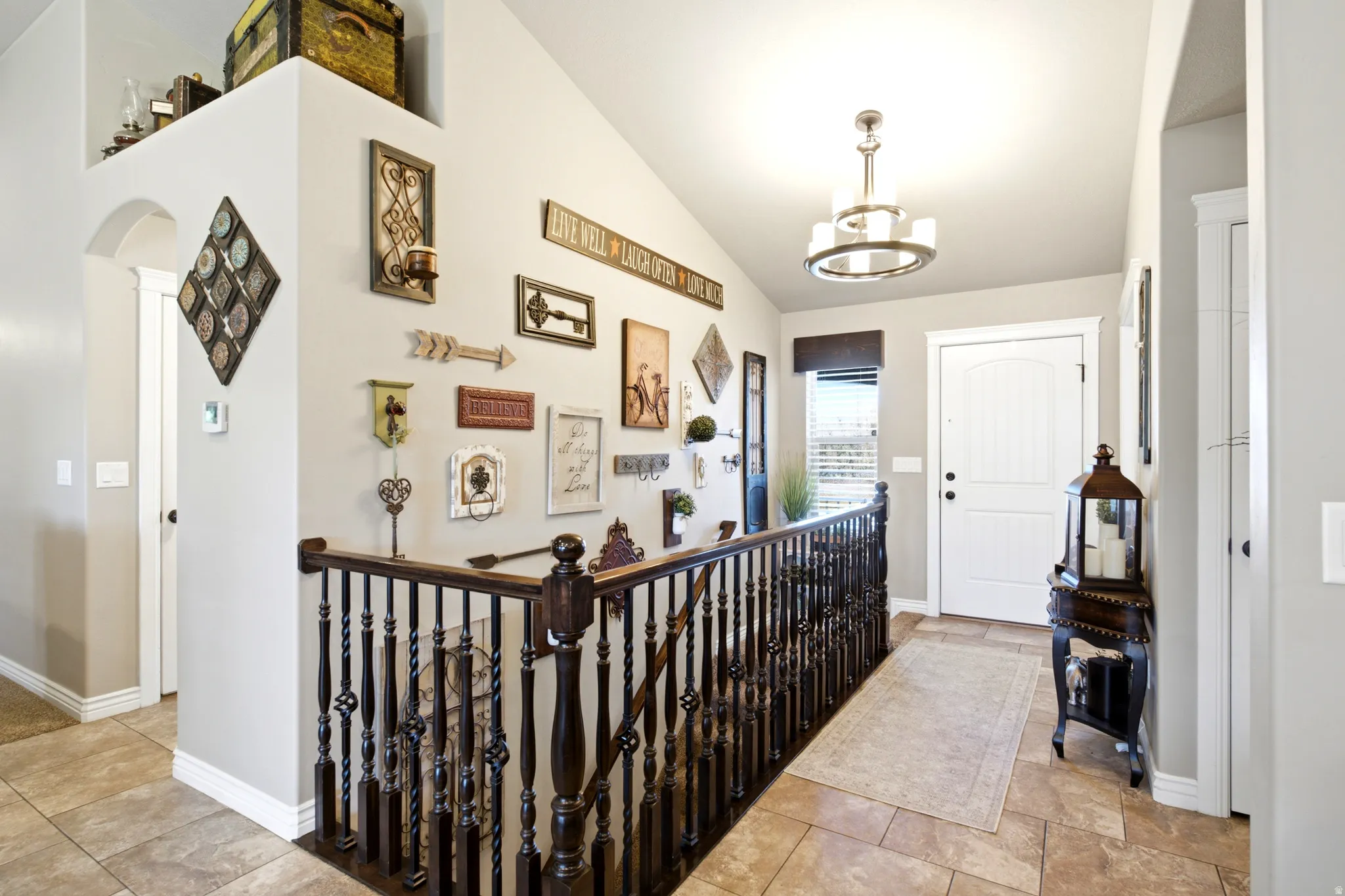 Entryway featuring tile flooring, a white paneled door, a decorative chandelier, and a wood-finish staircase with wrought iron balusters
