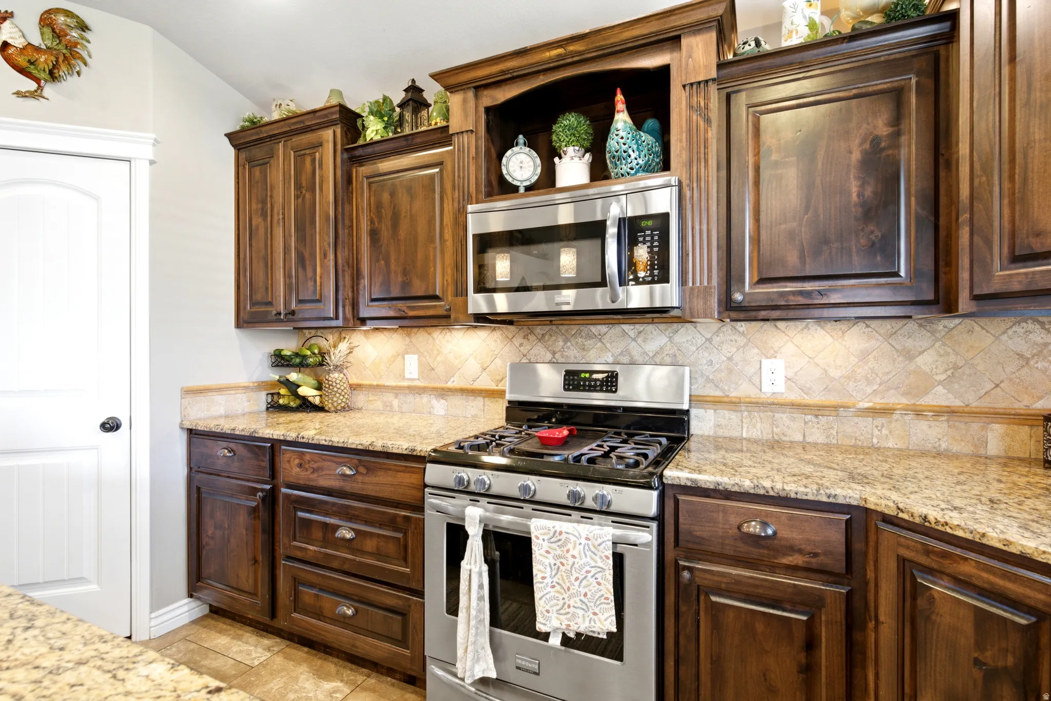 Wood-finish cabinetry, stainless steel appliances, granite countertops, and tile backsplash