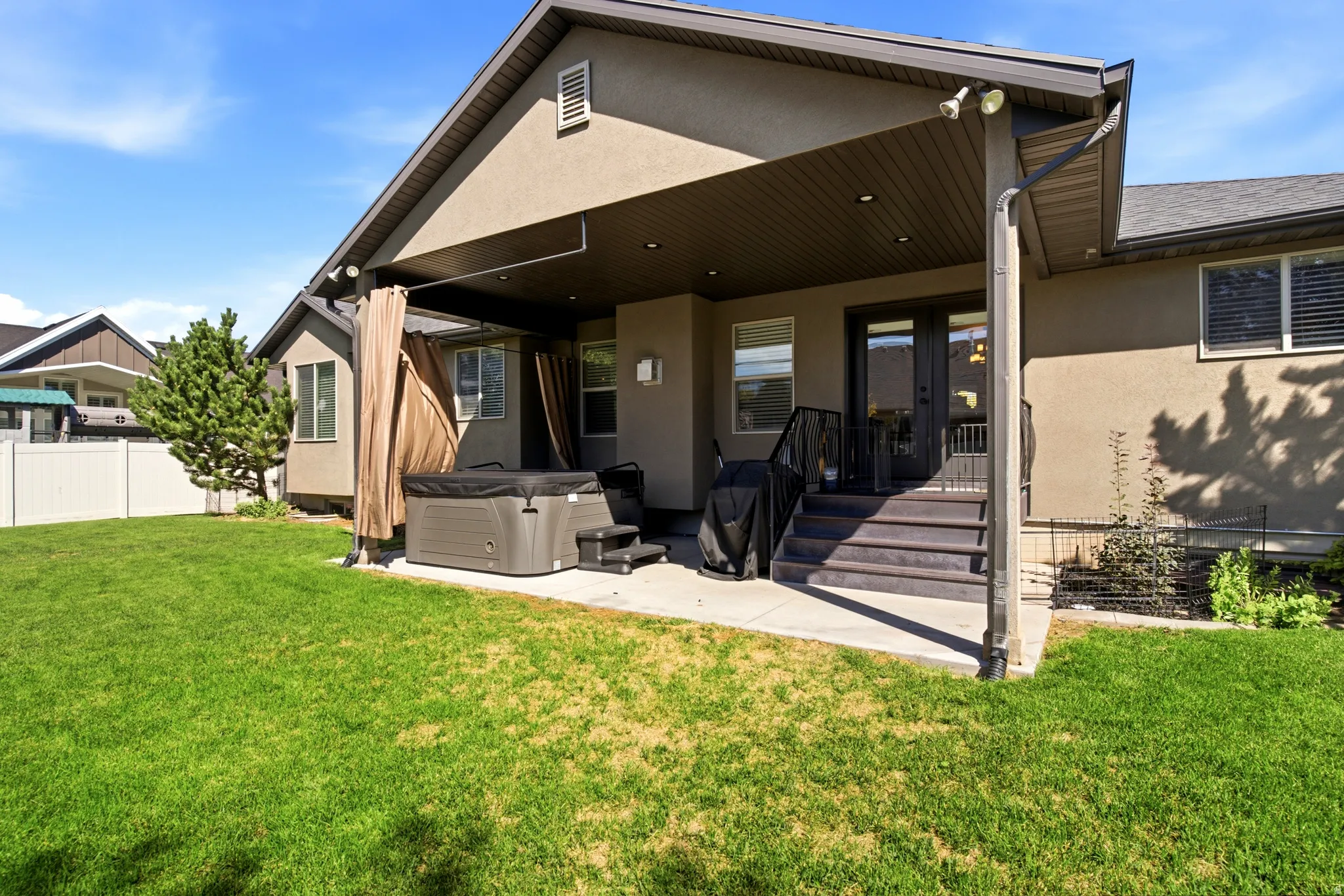 Expansive backyard featuring a covered patio, concrete steps, a privacy fence, and mature landscaping