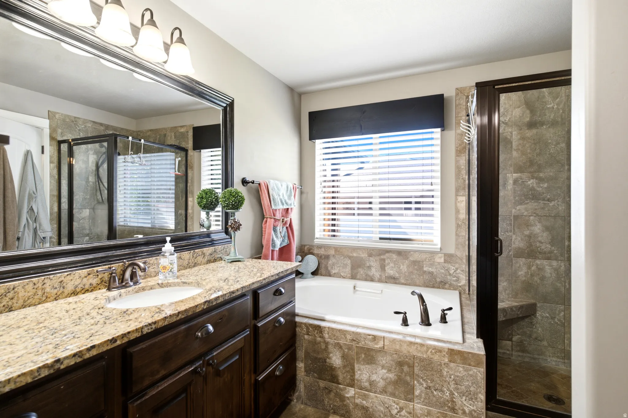 Spacious bathroom with a large vanity featuring a light-toned countertop and dark wood-finish cabinetry