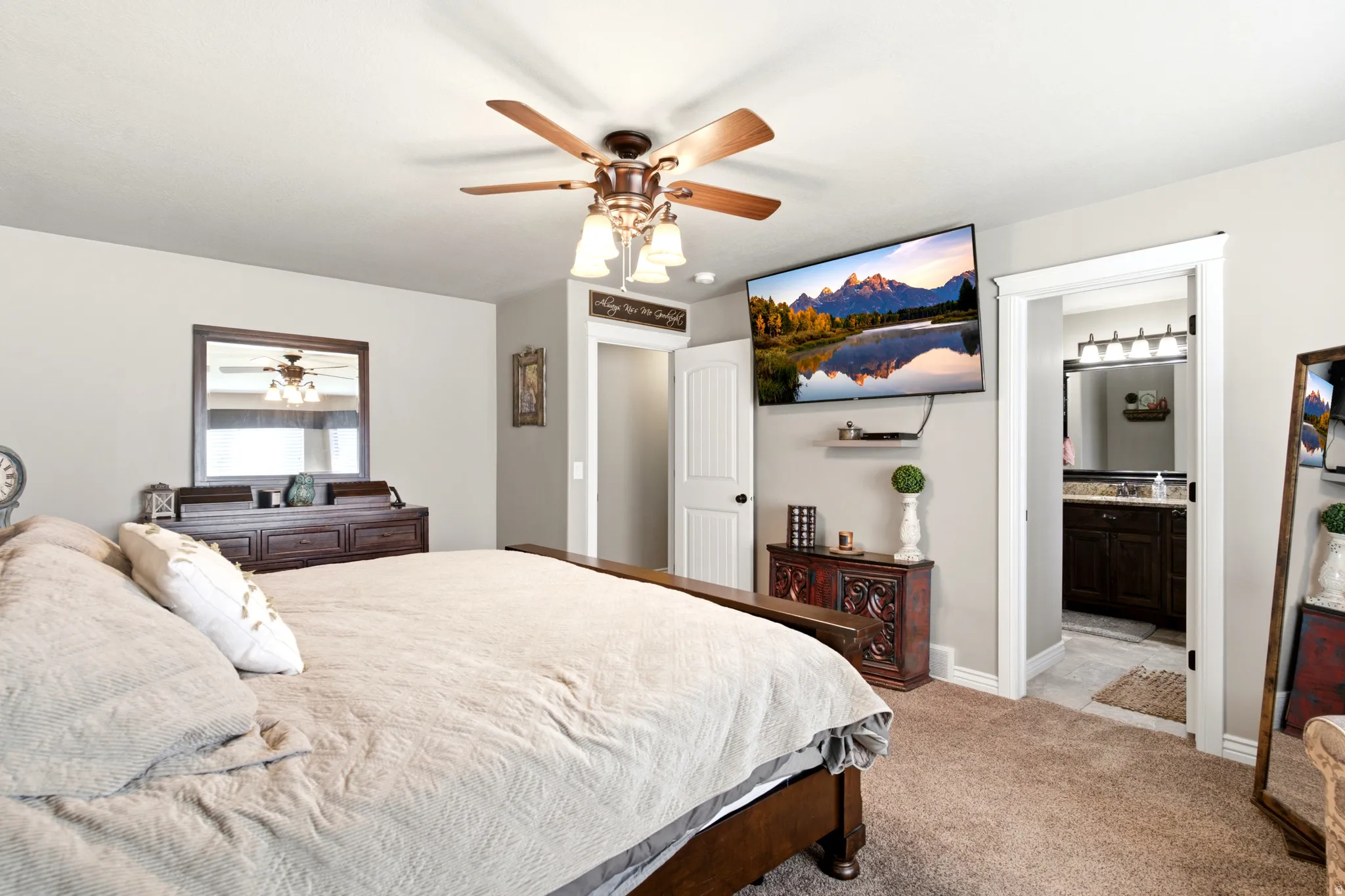 Carpeted bedroom featuring a ceiling fan with light fixture and a wall-mounted television