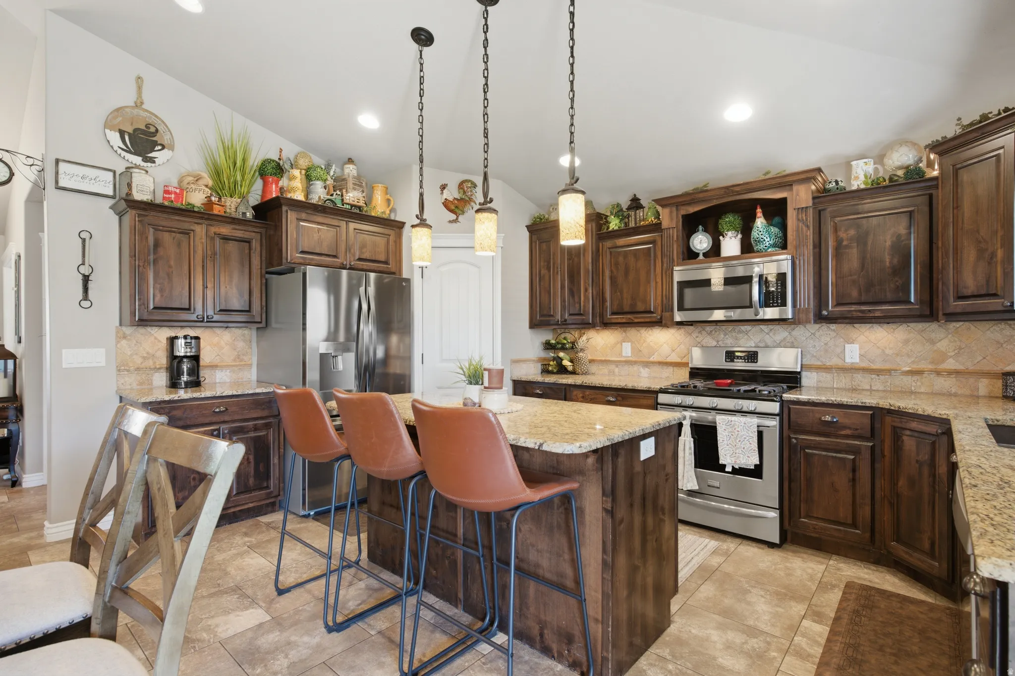 Kitchen featuring dark wood cabinetry, light granite countertops, stainless steel appliances, and a tiled backsplash