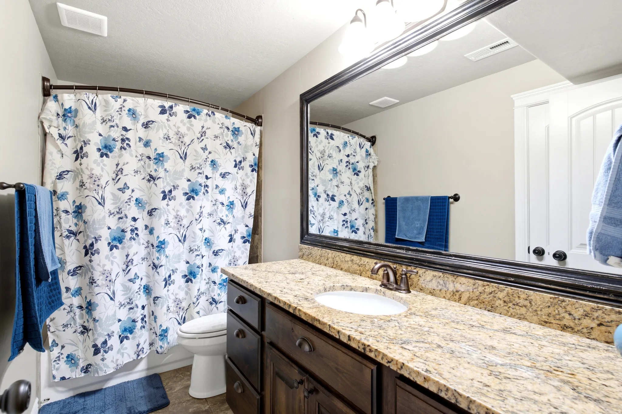 Bathroom featuring a single vanity with an integrated sink, granite countertop, and dark wood-finish cabinetry