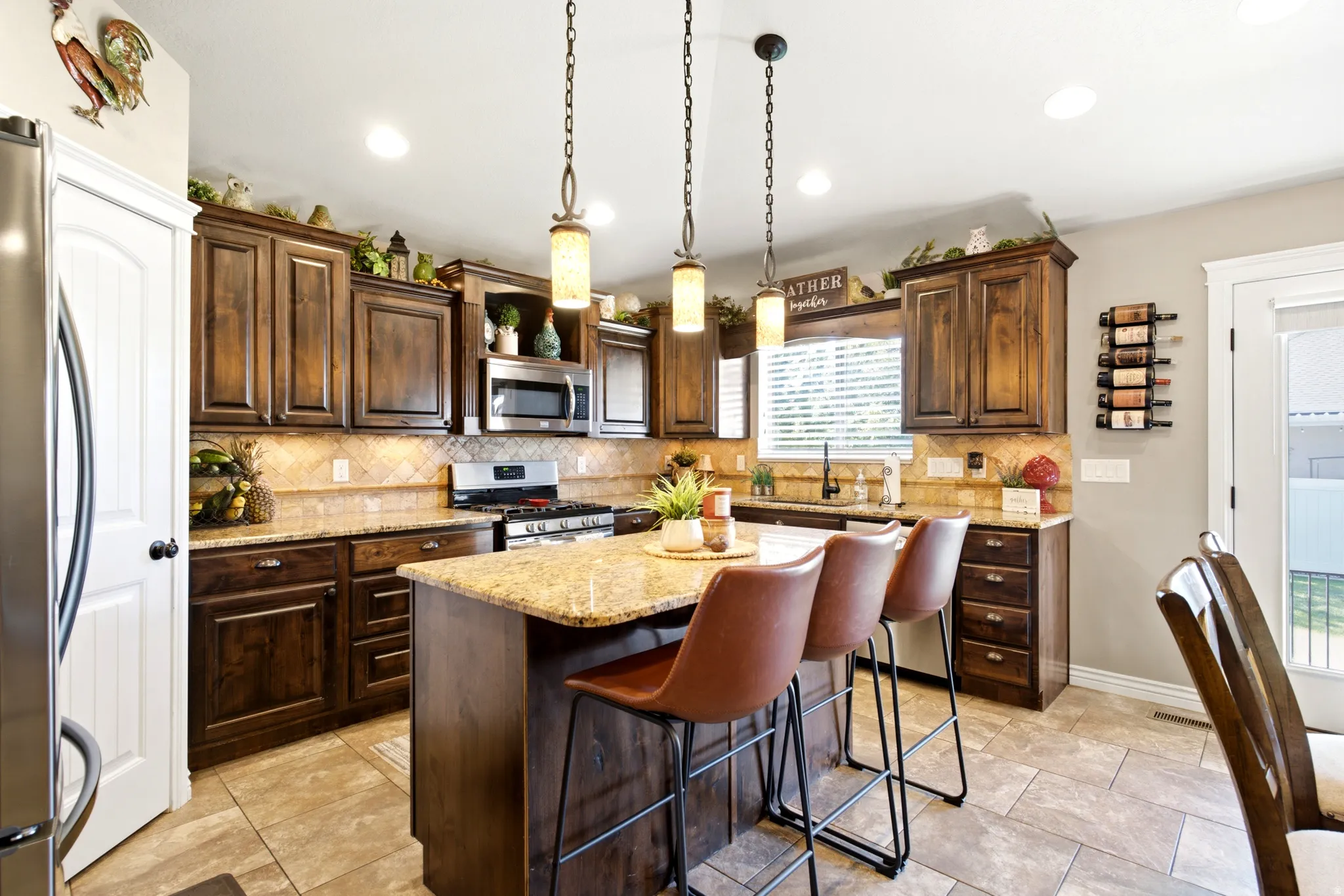 Kitchen featuring dark wood cabinetry, a central island with a stone countertop, stainless steel appliances, and tiled flooring